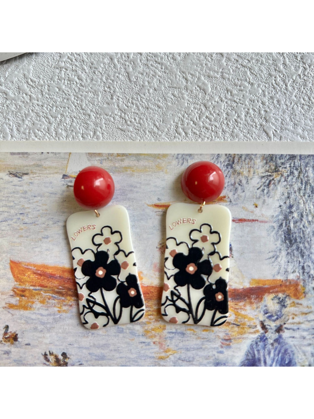Model wearing Earwish Graphic Floral Drop Earrings with pink flowers and green leaf accents