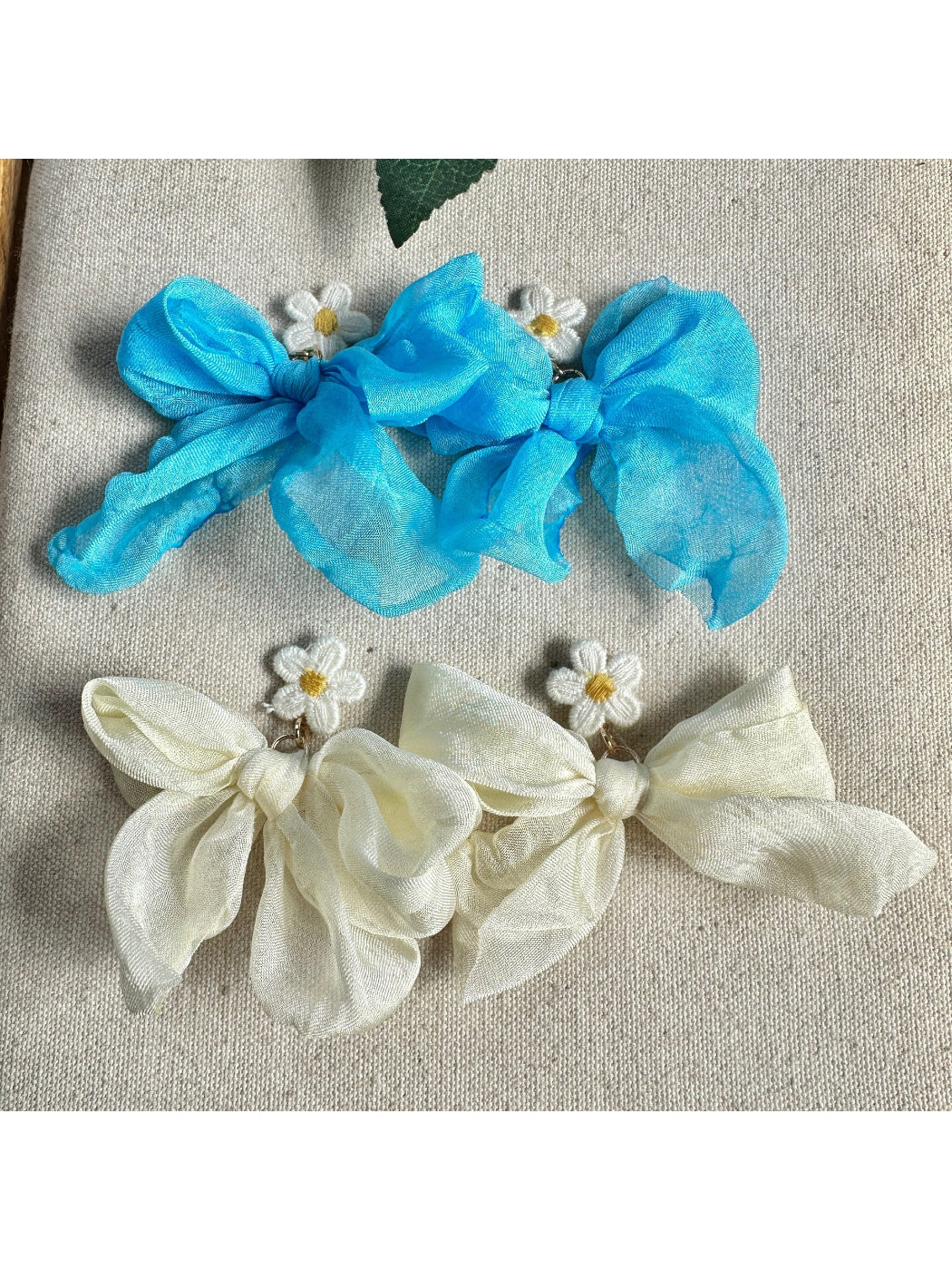 Earwish soft ribbon daisy earrings worn on an ear, highlighting delicate design and size