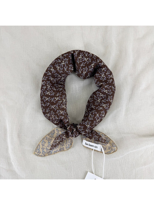 Close-up of Scarvii scarf fabric with small floral patterns and detailed border