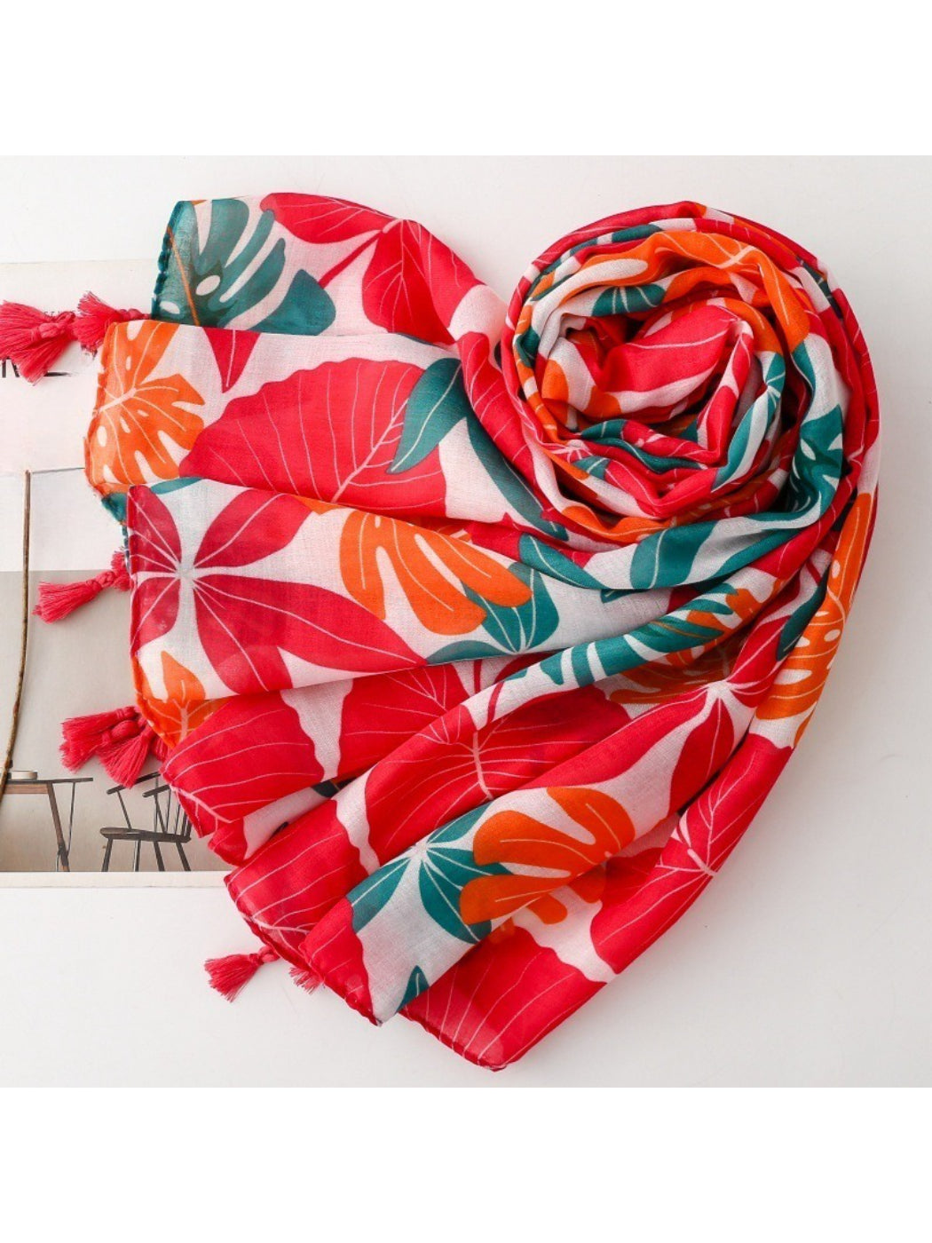 Scarvii scarf laid flat displaying full botanical print with green leaves and orange accents on white