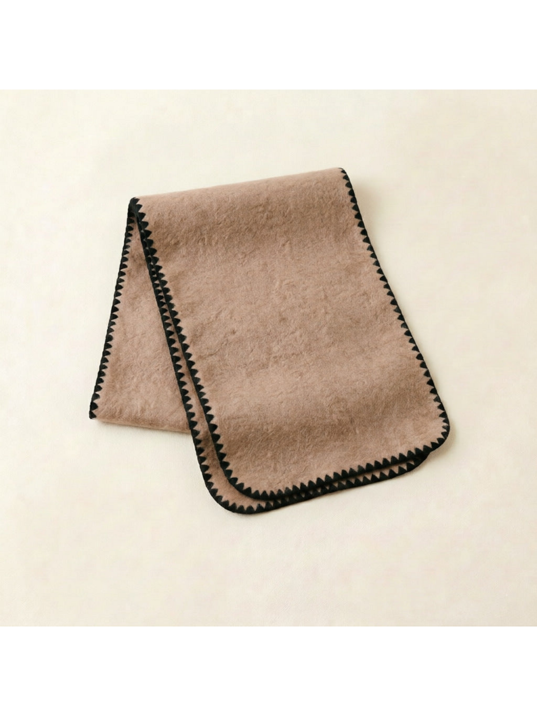 Beige scarf with black triangular edging and rounded corners, folded view