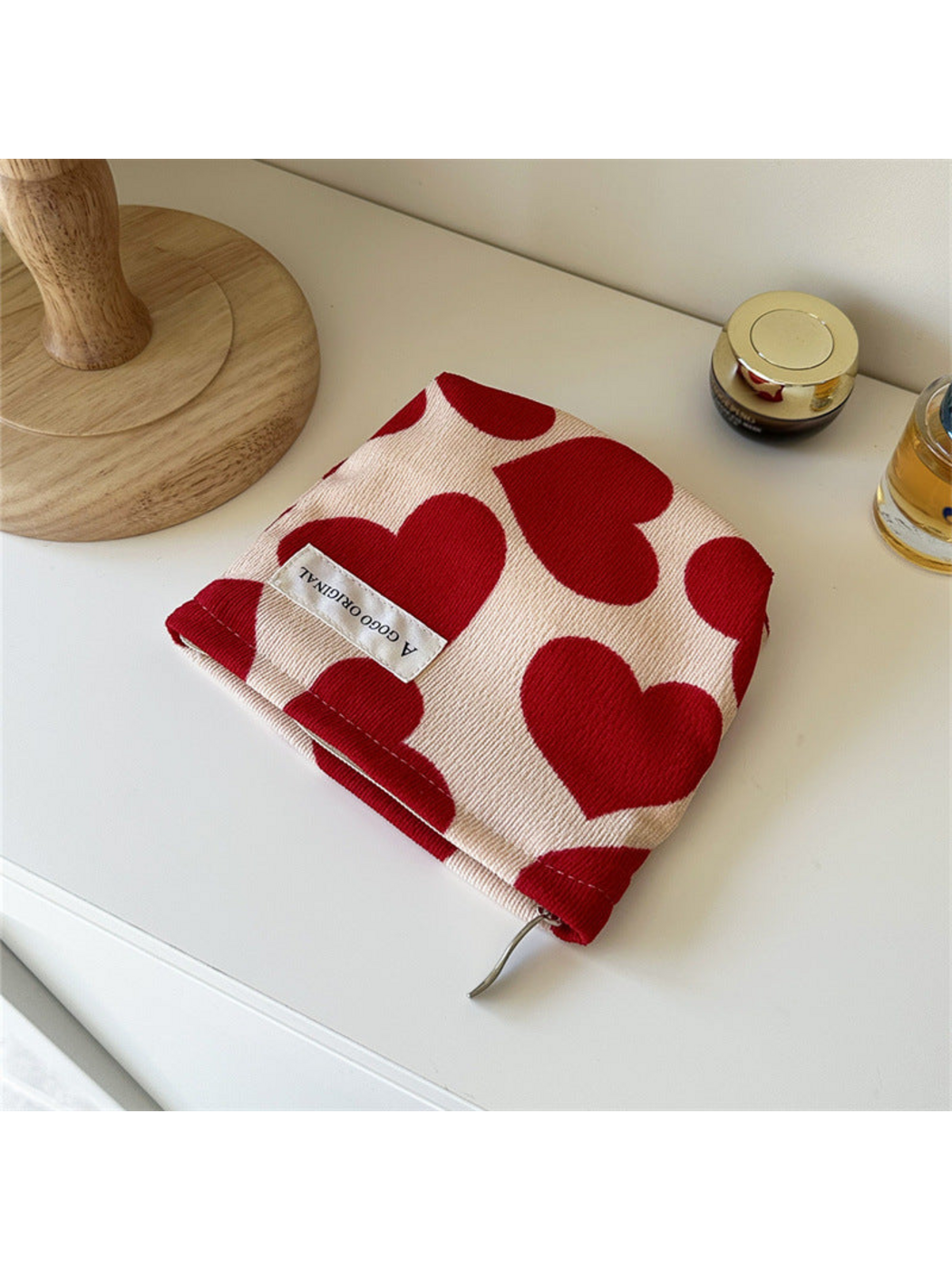 Trapezoid cream pouch with red hearts and a white front label, viewed from above