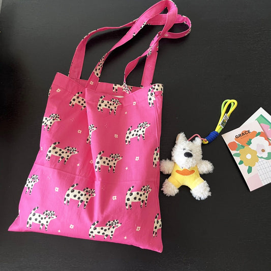 Close-up of pink fabric featuring detailed puppy illustrations on tote
