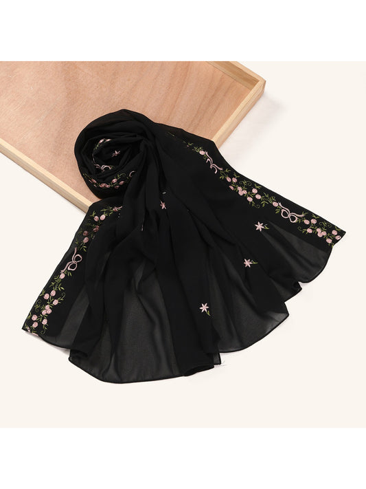 Close-up of floral embroidery detail on soft scarf fabric