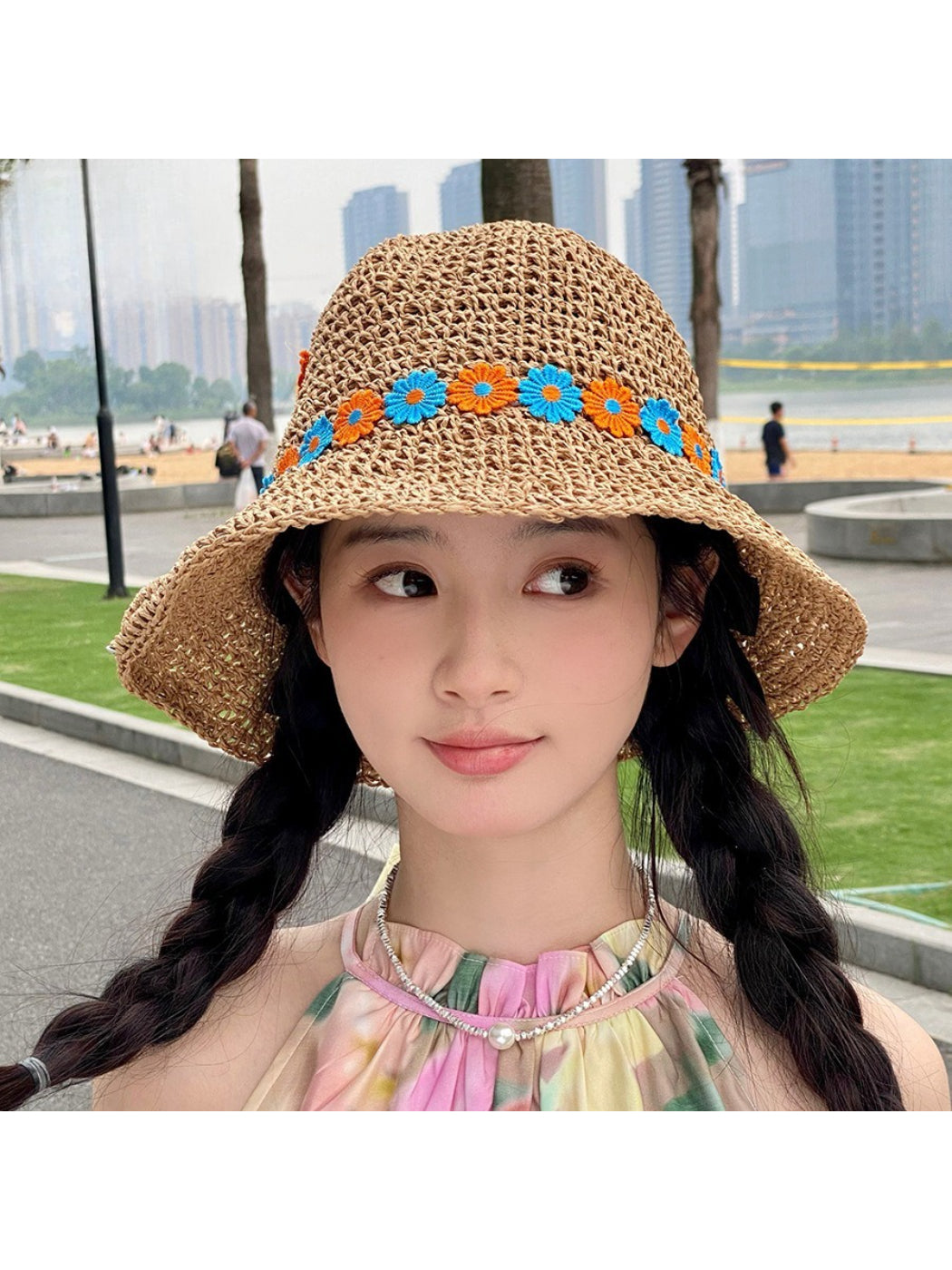 Model wearing Haila Daisy Chain woven sun hat outdoors with blue sky background