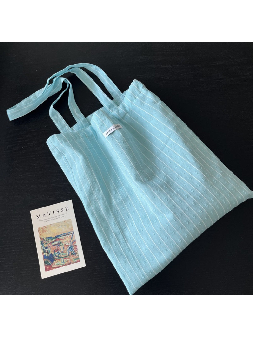 Cosbai sky blue tote bag held by hand showing size and portability