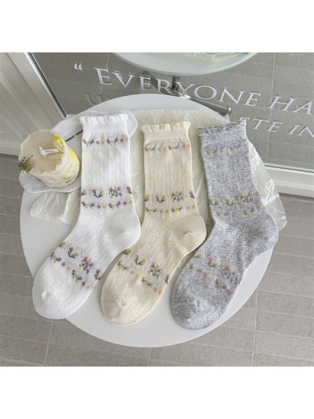 Rufia floral pointelle crew socks folded neatly on a wooden surface