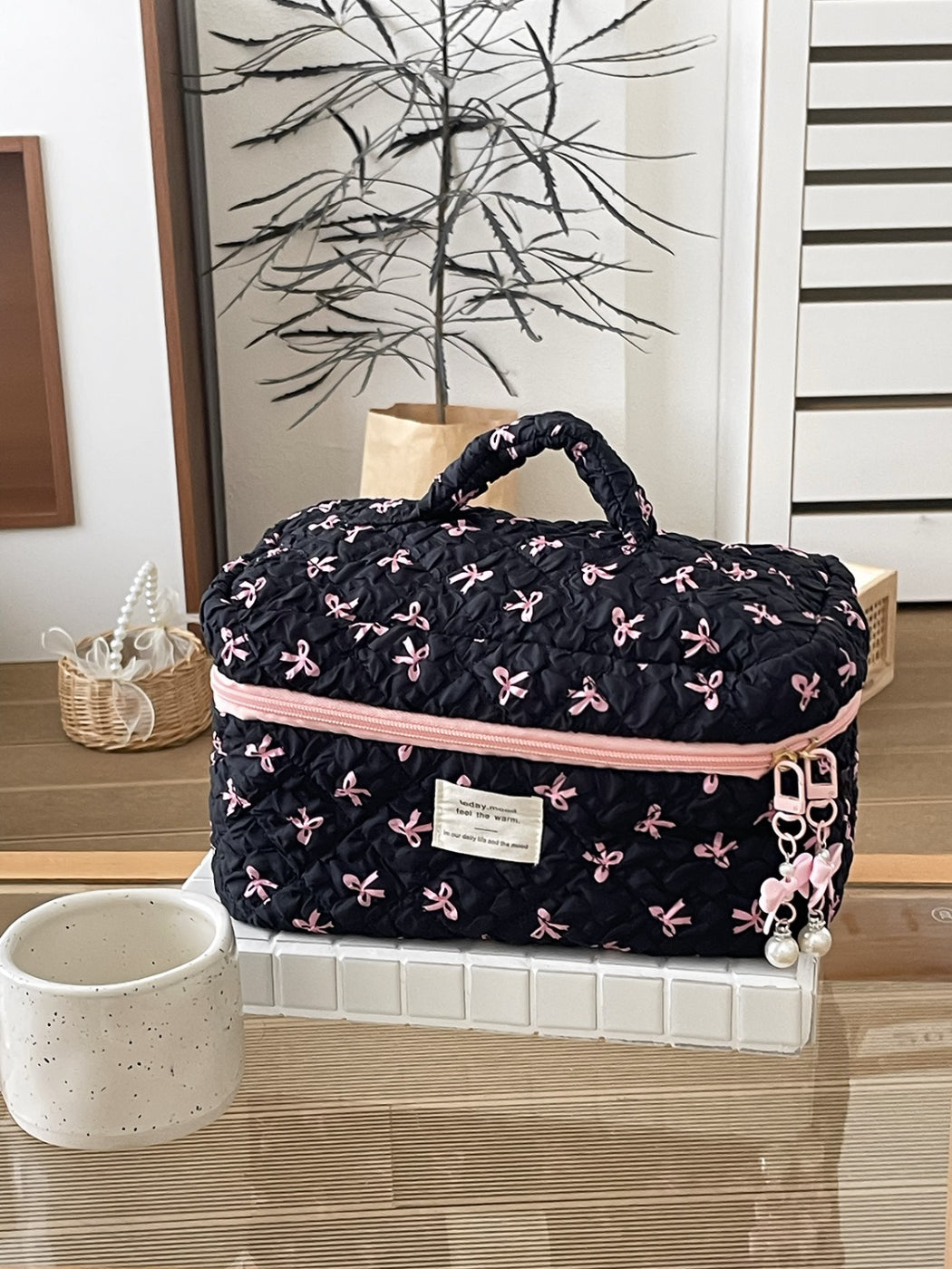 Cosbai travel makeup bag placed next to travel essentials on a wooden surface