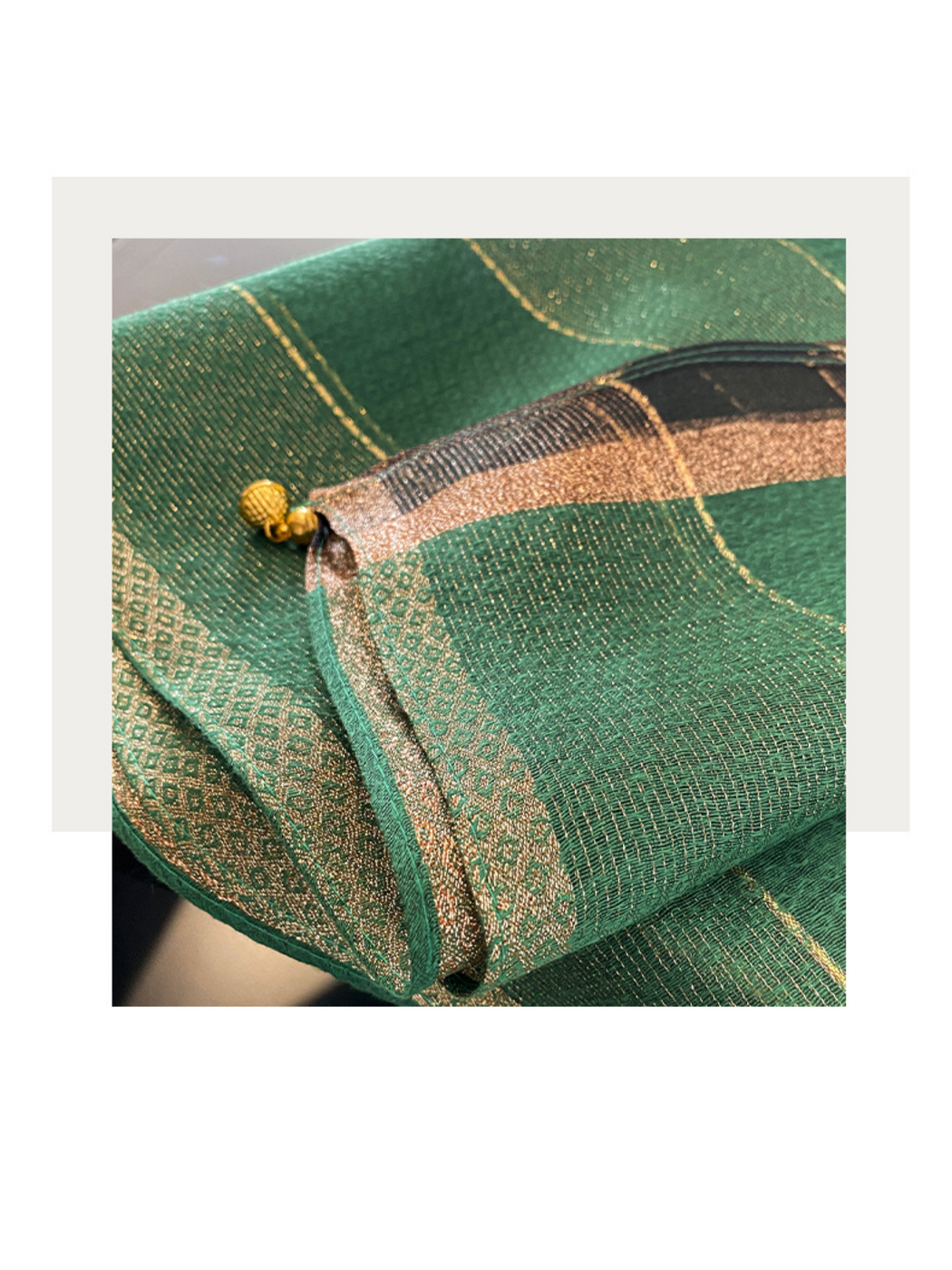 Close-up of Green scarf showing open weave, a geometric border and a gold-tone end ornament