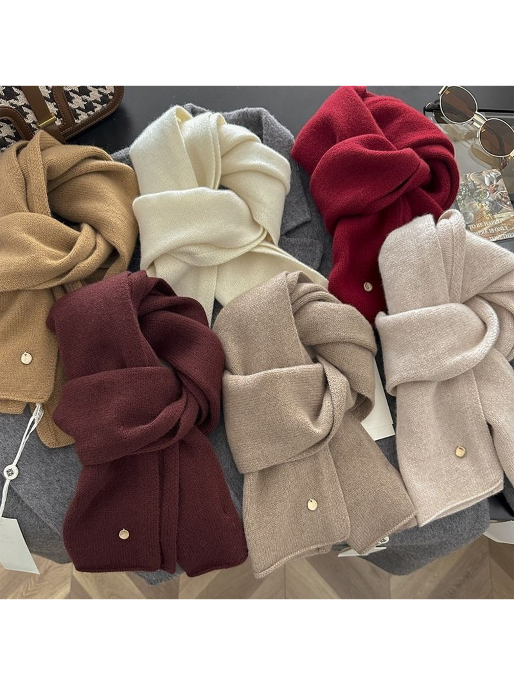 Solid-color scarves in neutral and red shades displayed together in looped arrangements