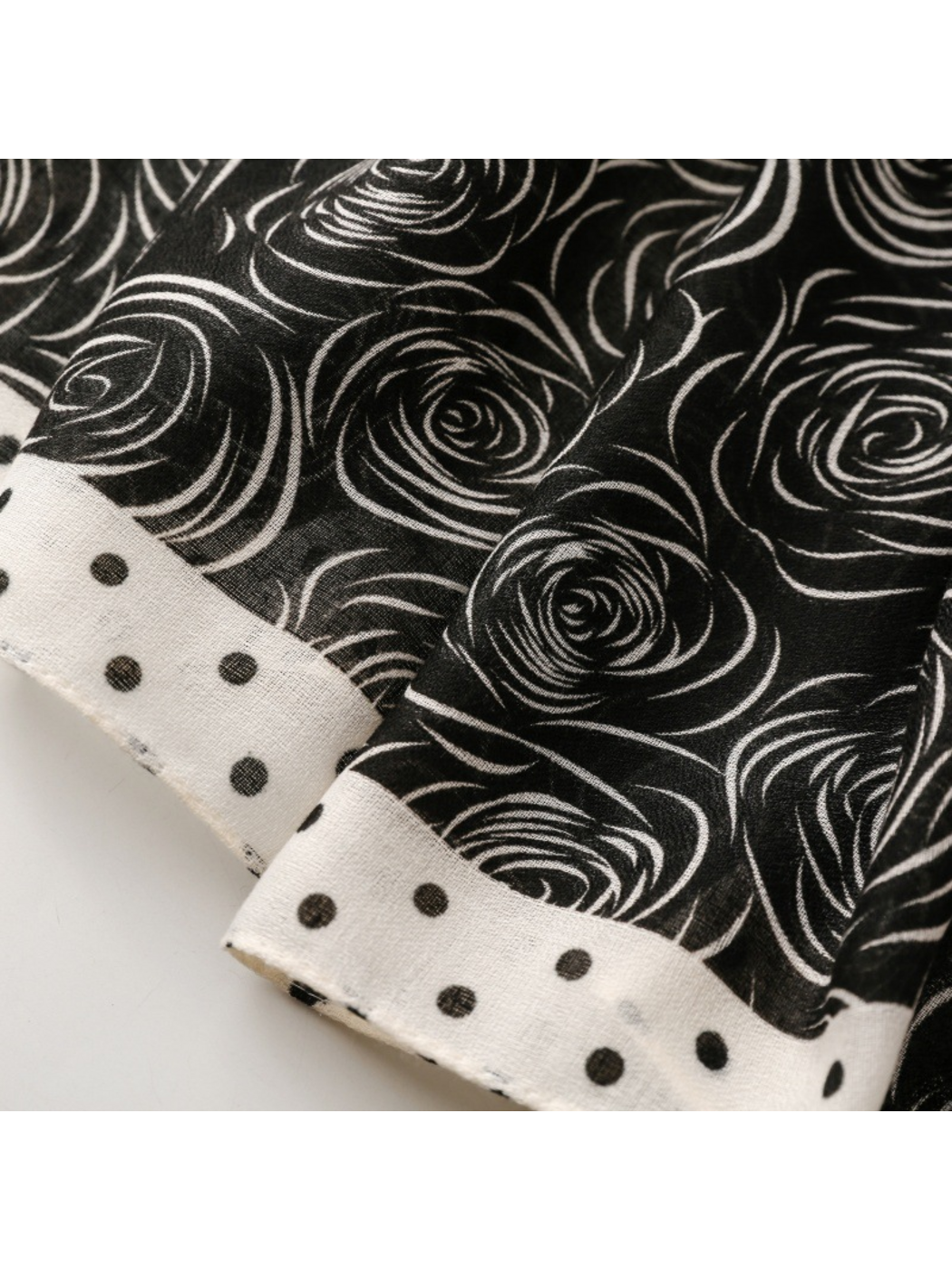 Close-up of white rose motifs on a dark ground beside a contrasting dotted border