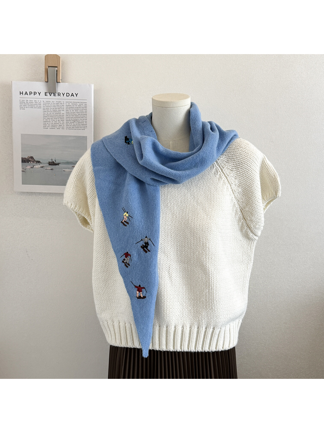 Sky Blue embroidered knit scarf wrapped around the neck with one end hanging in front