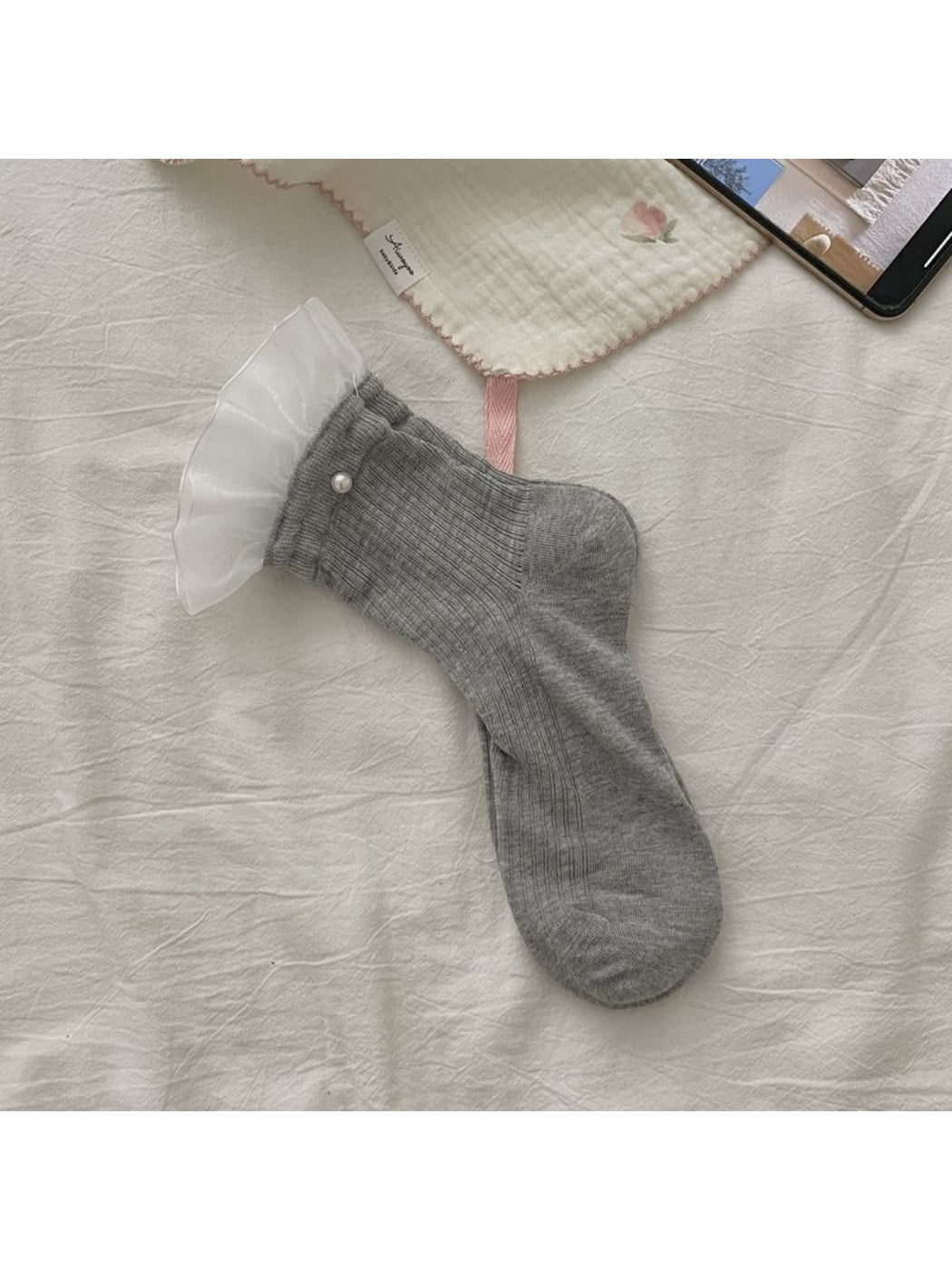 Rufia sheer crew socks with ruffle trim displayed on wooden surface