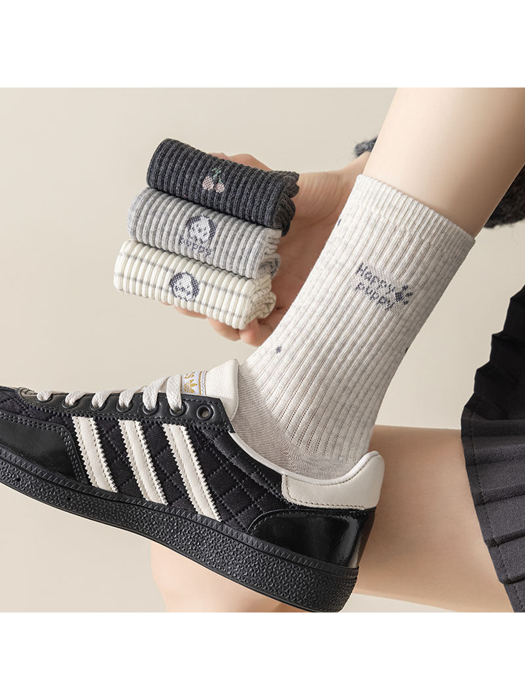 Light gray Happy Puppy sock worn with a sneaker while folded socks are held