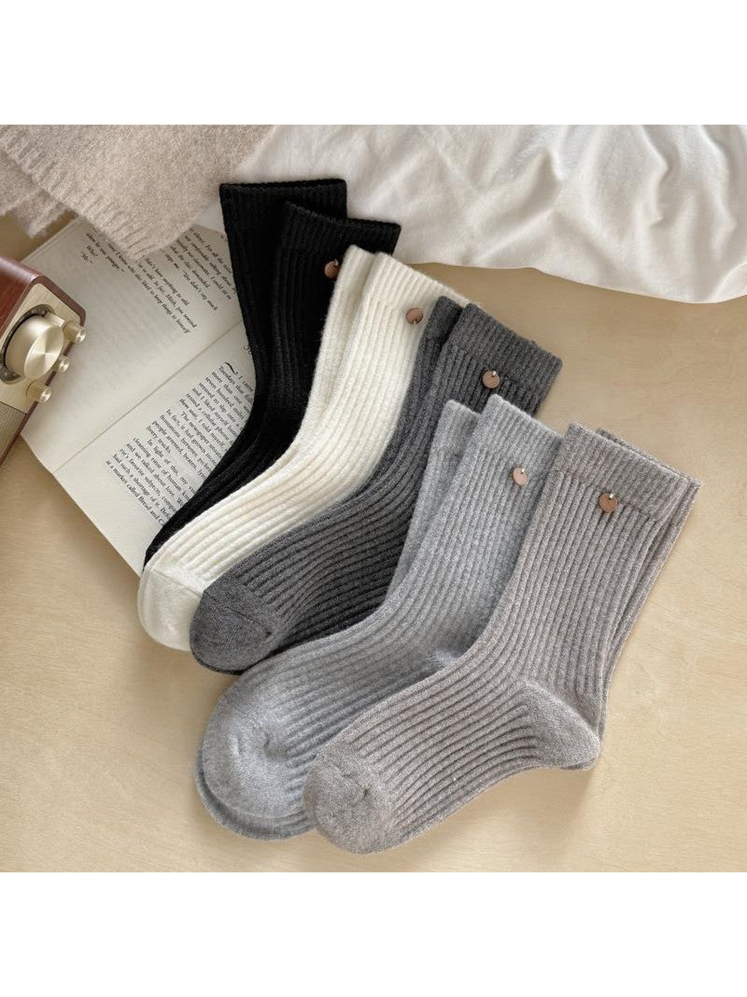 Overlapping ribbed socks in five colors arranged diagonally with round cuff ornaments visible.