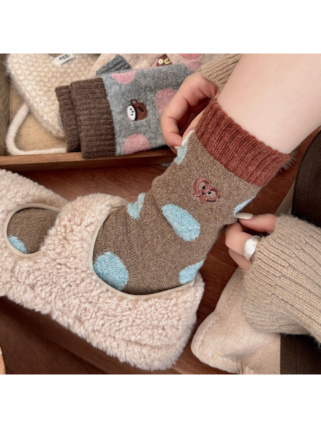 Person adjusting a Pretzel sock with light blue polka dots while wearing a cream slipper.