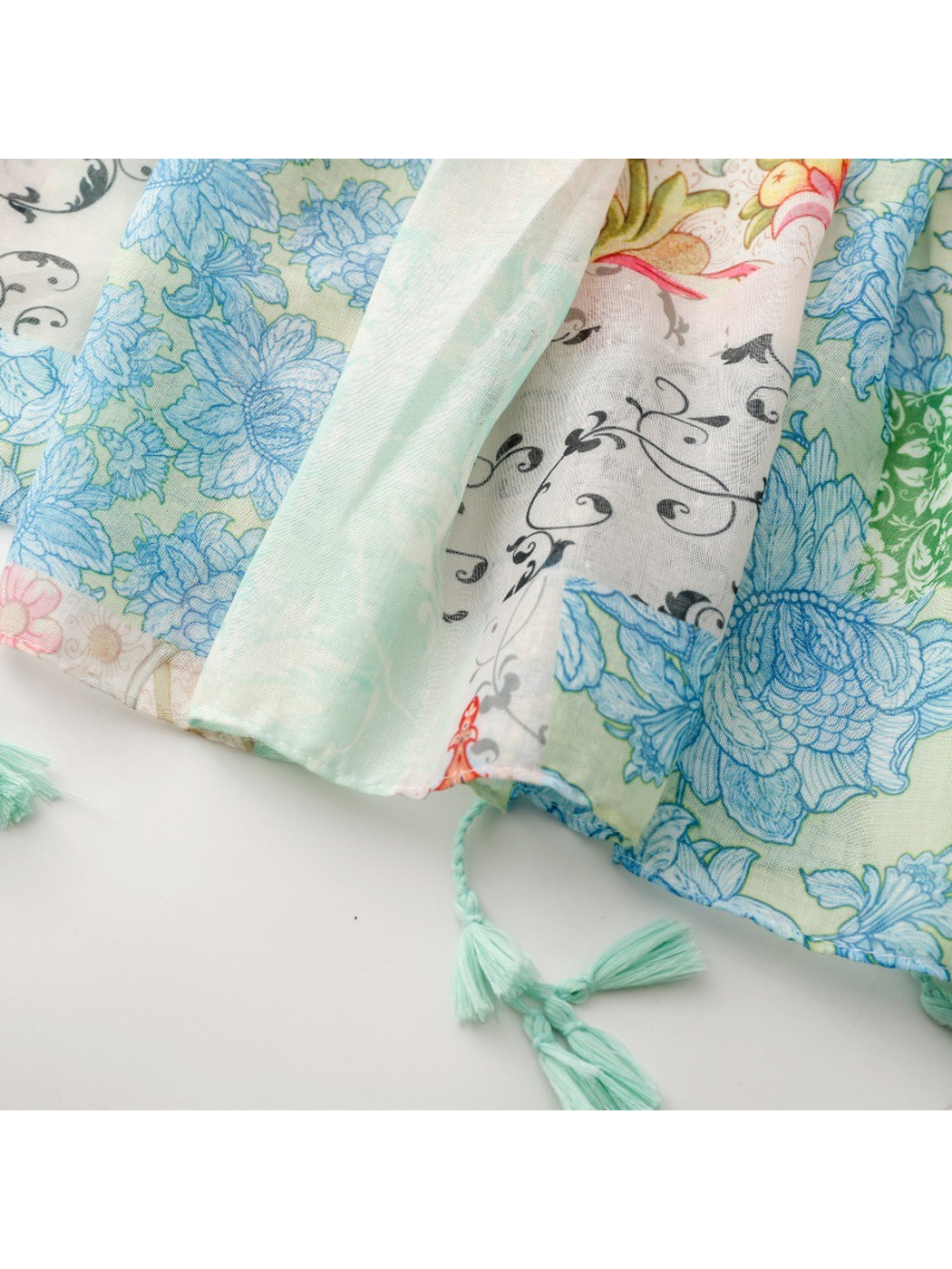 Close-up of mint tassels beside blue floral and black scrolling-vine panels
