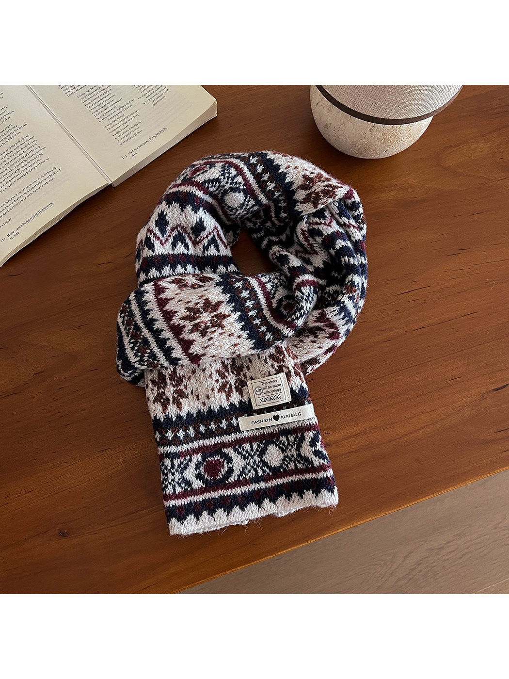 Ivory scarf with a navy, burgundy and brown geometric pattern on a wooden table