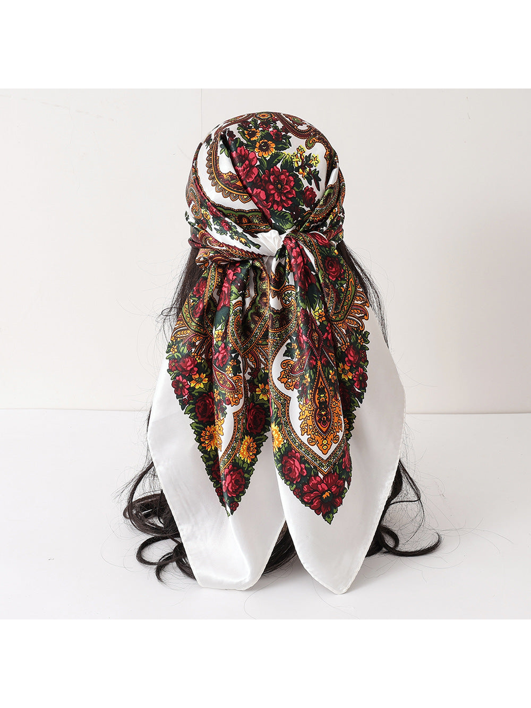 White floral paisley scarf folded and tied over a head form