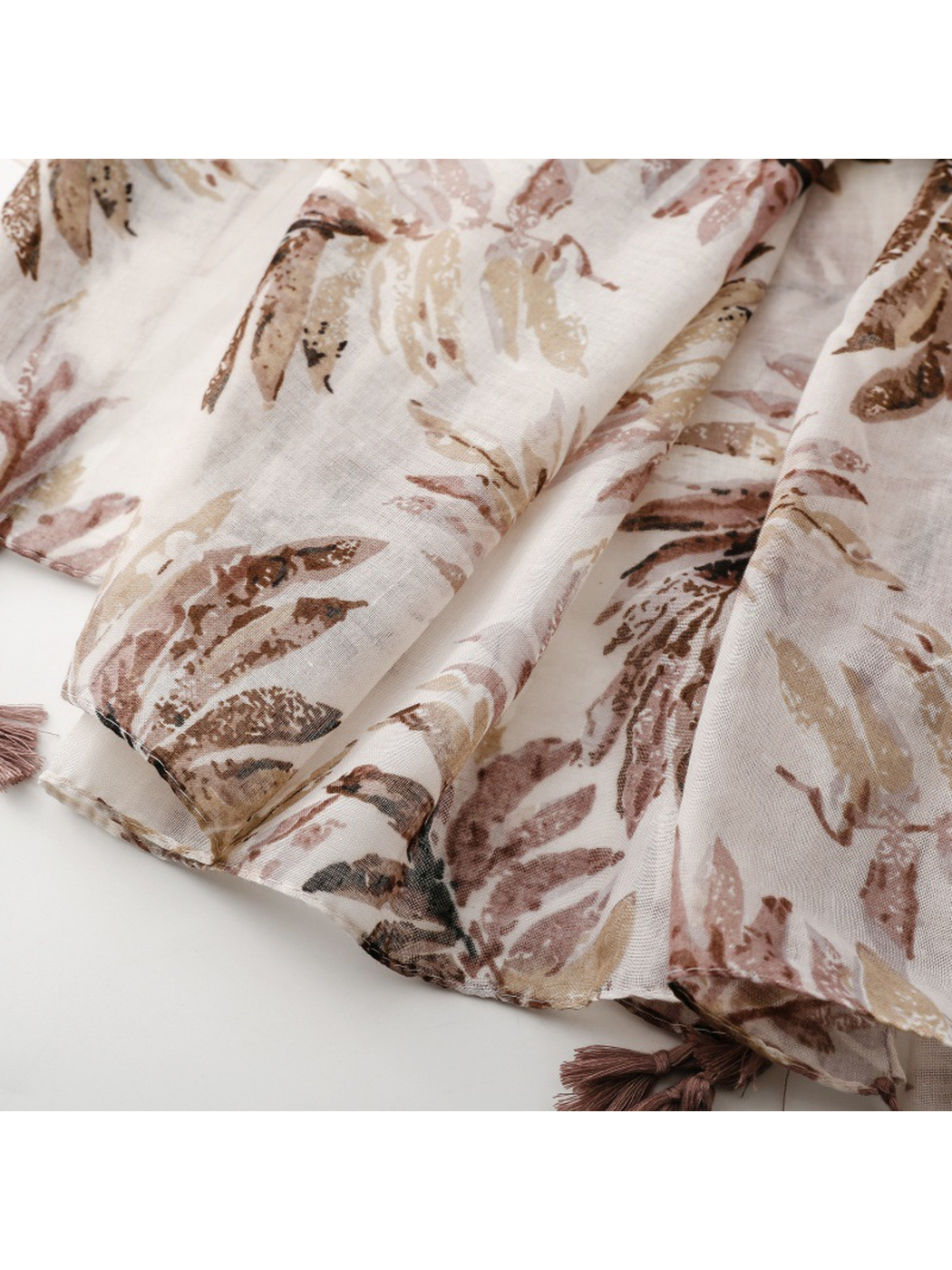 Close-up of the scarf's narrow stitched hem, botanical print, and corner tassel