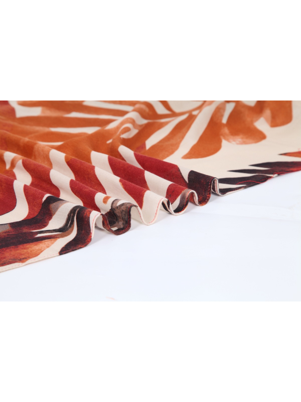 Close-up of the orange printed scarf edge arranged in rippling folds