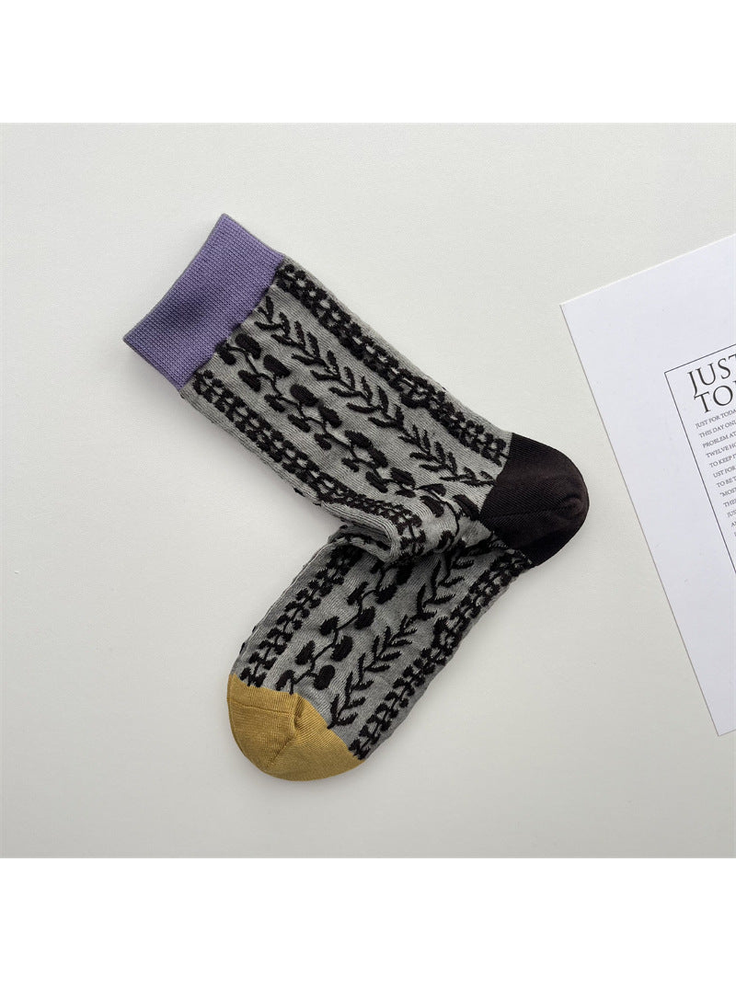 Gray vine-pattern crew socks with a lavender cuff and mustard toe