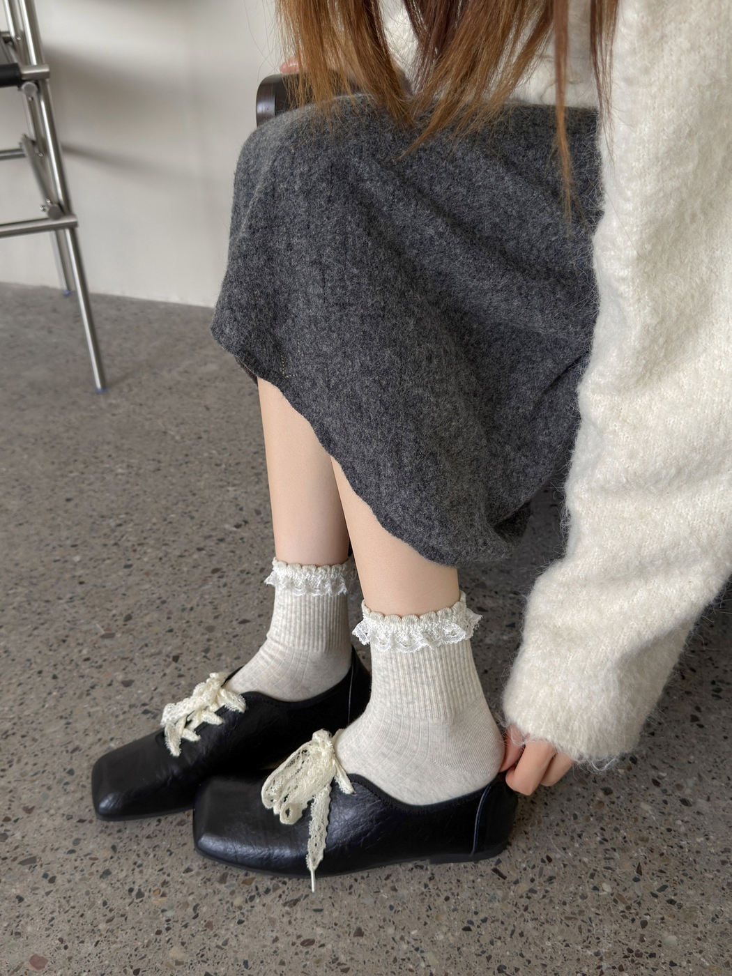 Light gray lace-trimmed crew socks styled with black lace-up shoes