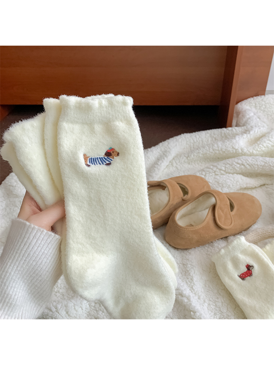 Close view of ivory fuzzy socks with blue-striped dog embroidery
