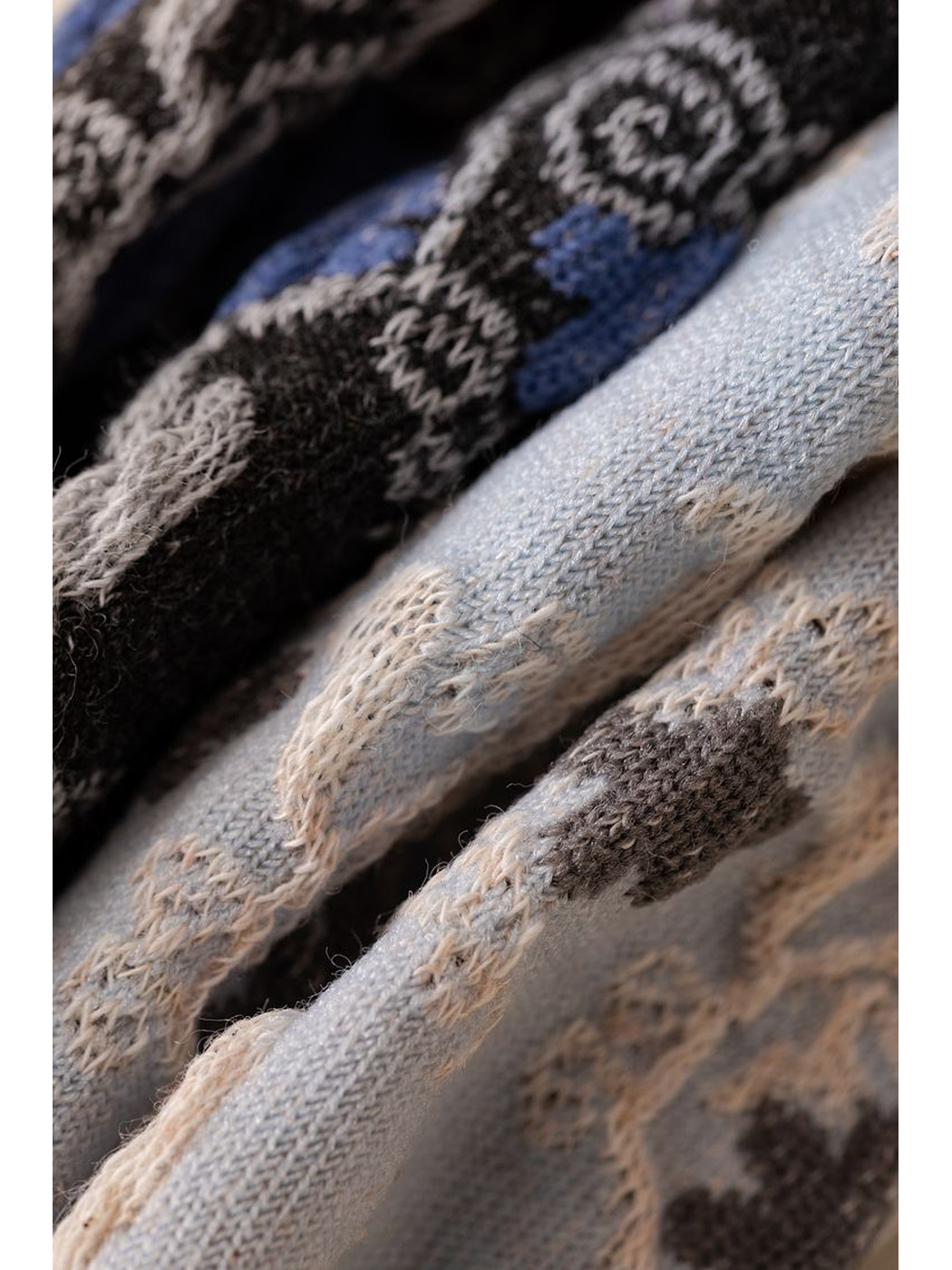 Macro close-up of raised motifs on black, blue, and pale blue-gray knit