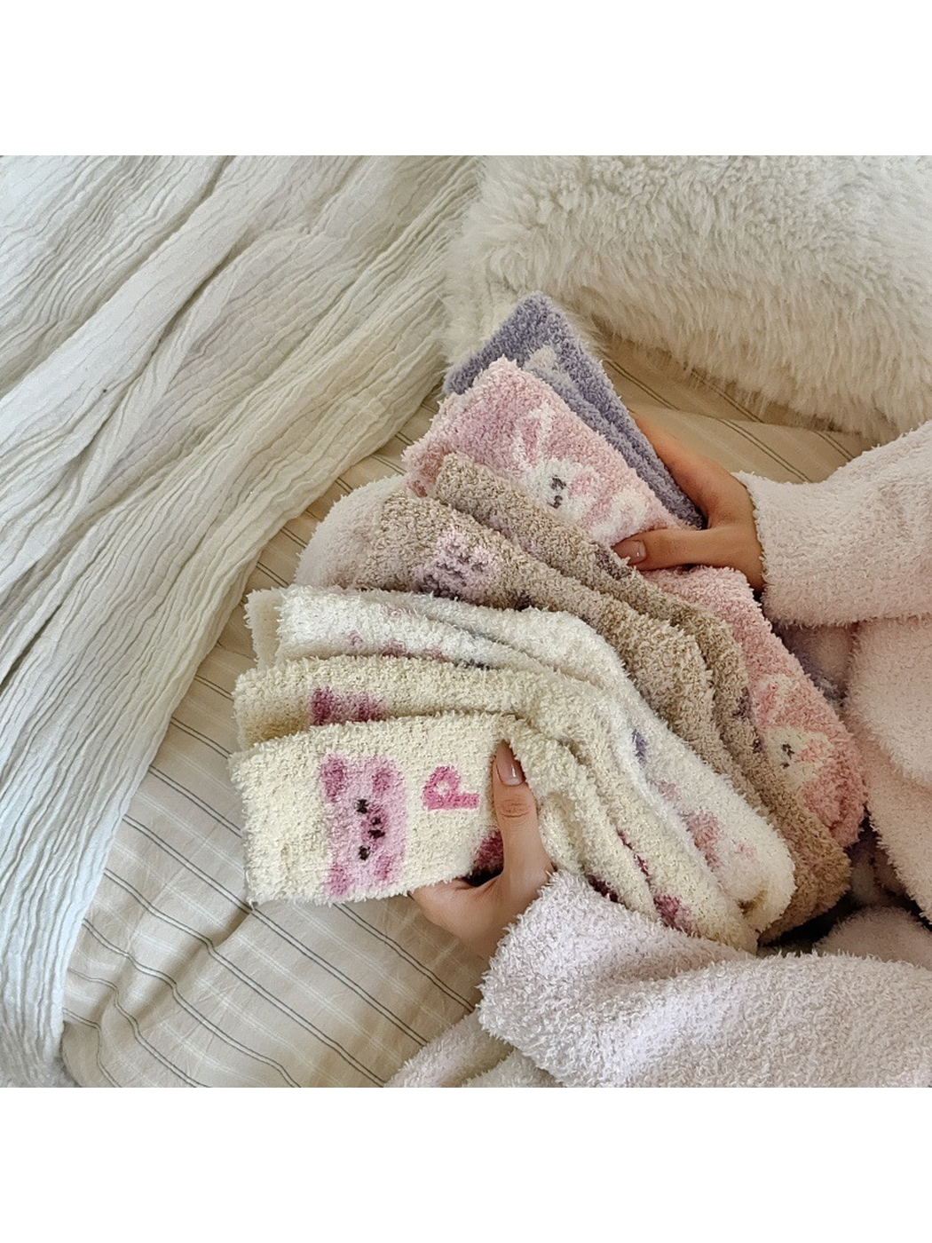 Assorted fuzzy patterned crew socks held together on a bed