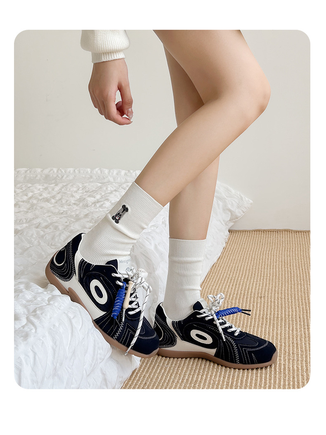 White embroidered crew socks worn with navy sneakers in a standing view