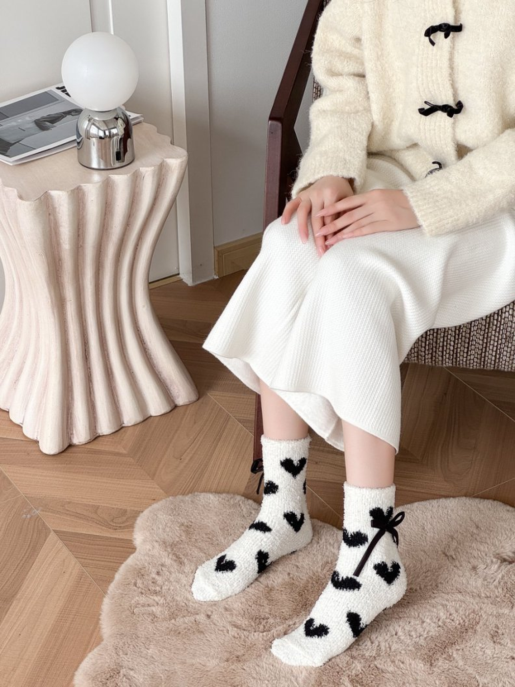 White fuzzy socks with large black hearts worn above the ankle