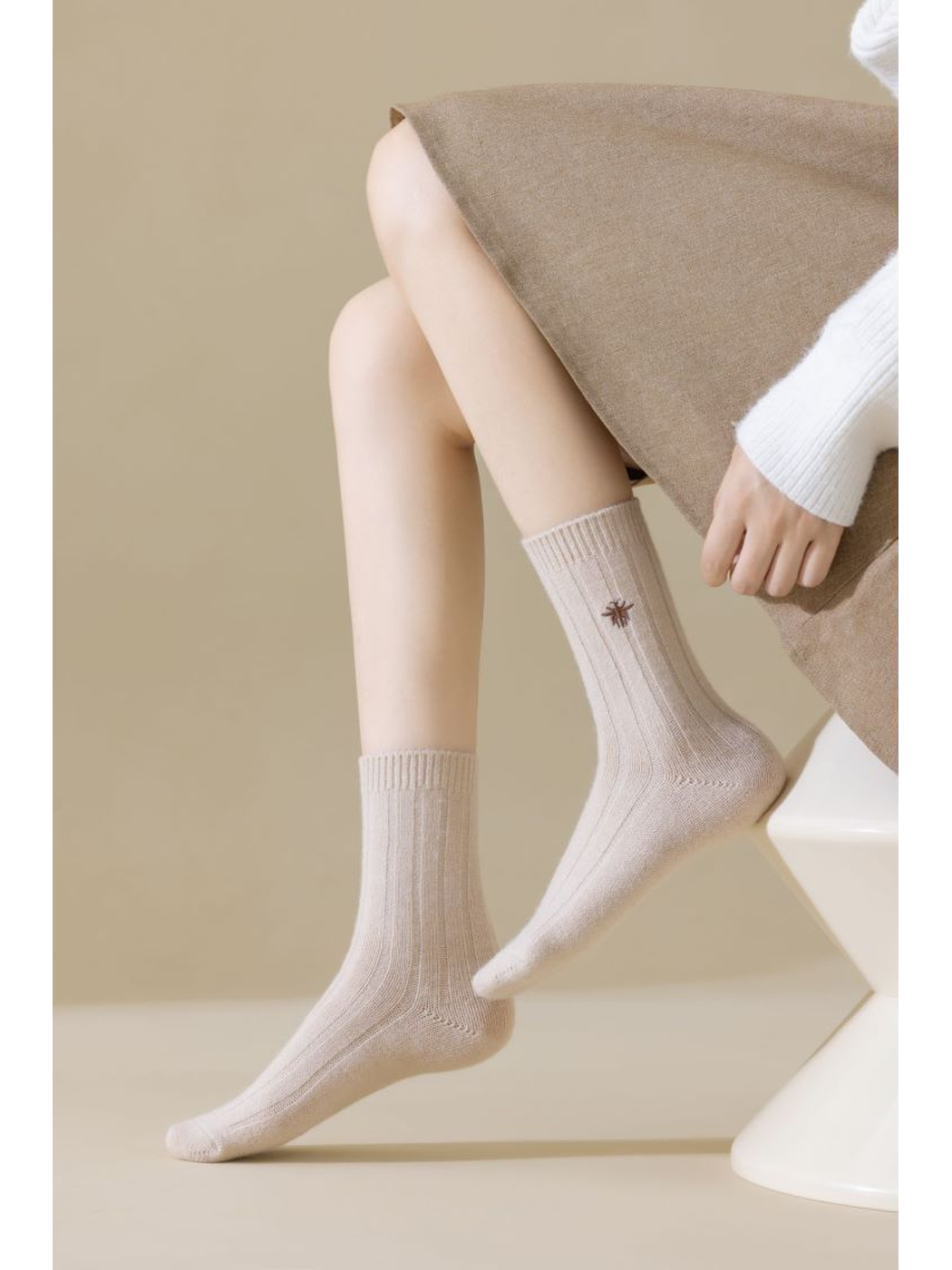 Light beige ribbed crew socks worn in a seated pose