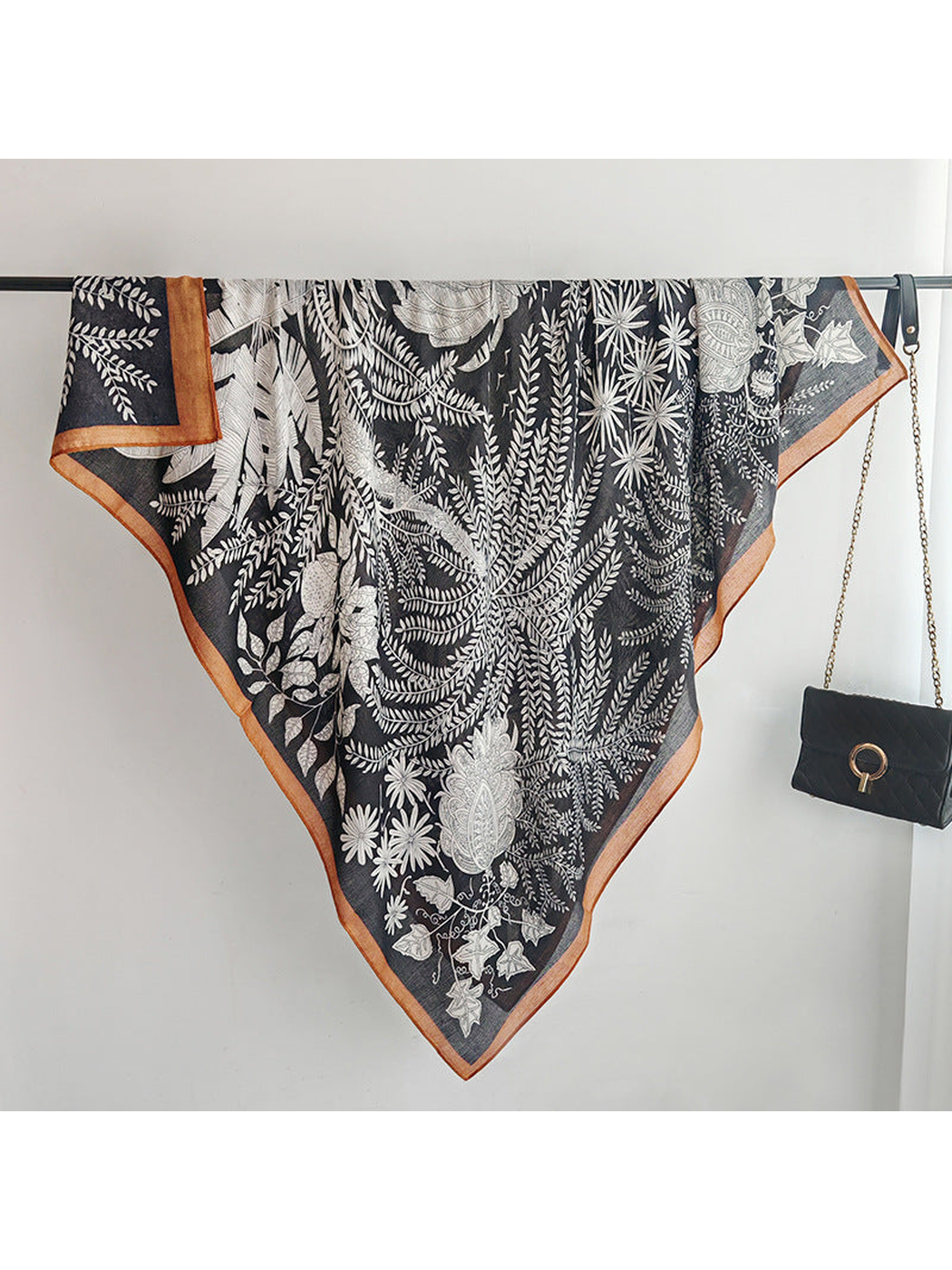 Black botanical square scarf fully draped over a display rail