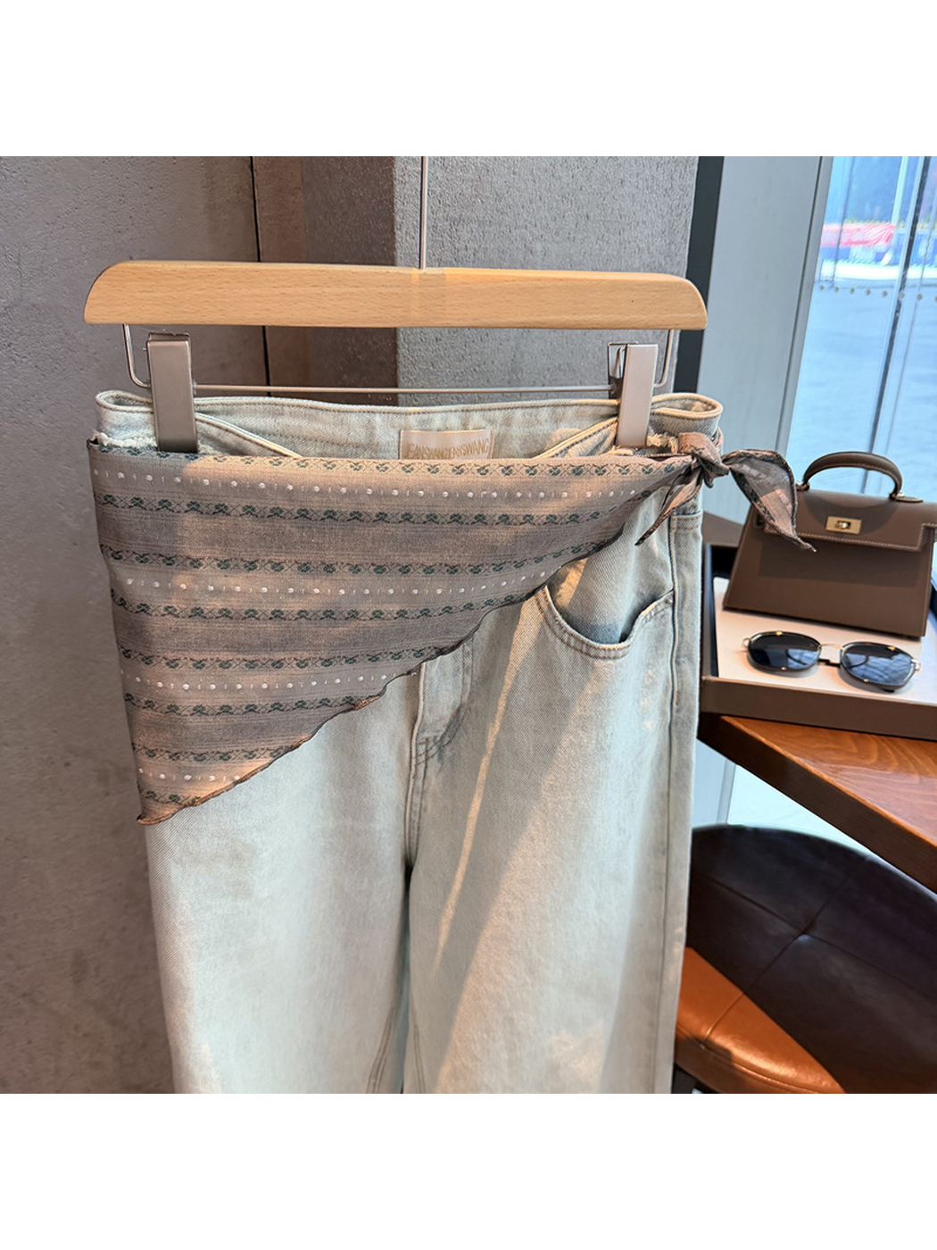 Gray striped scarf tied around the waist of light-wash jeans