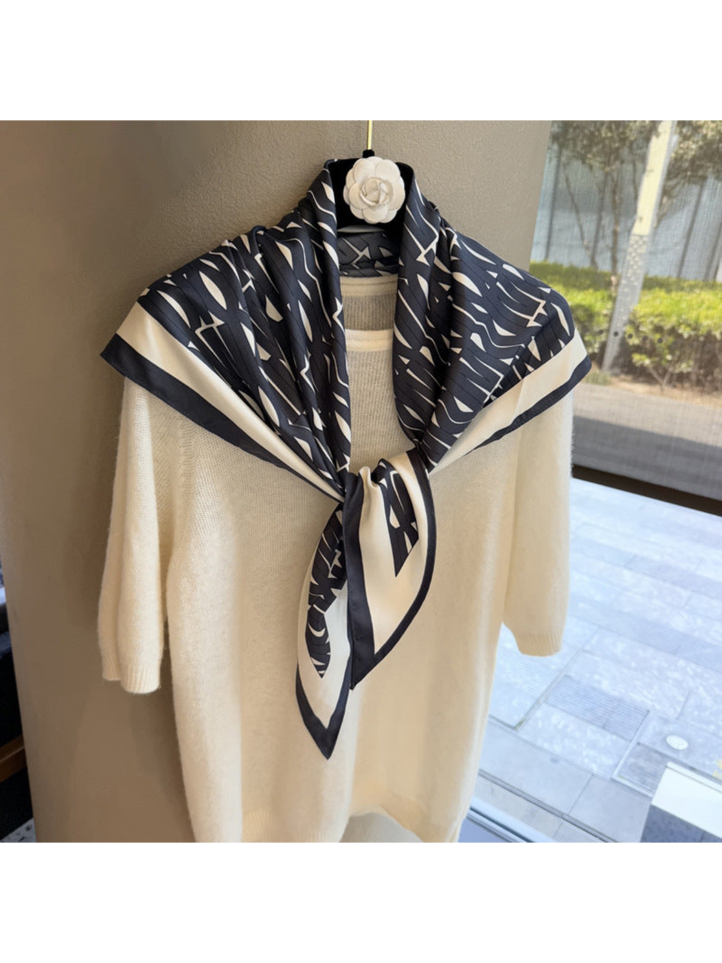 Black and ivory triangle scarf tied over a cream sweater