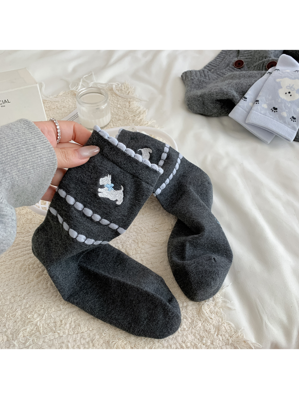 Close-up of dark gray crew socks with an embroidered white dog and raised light blue stripes