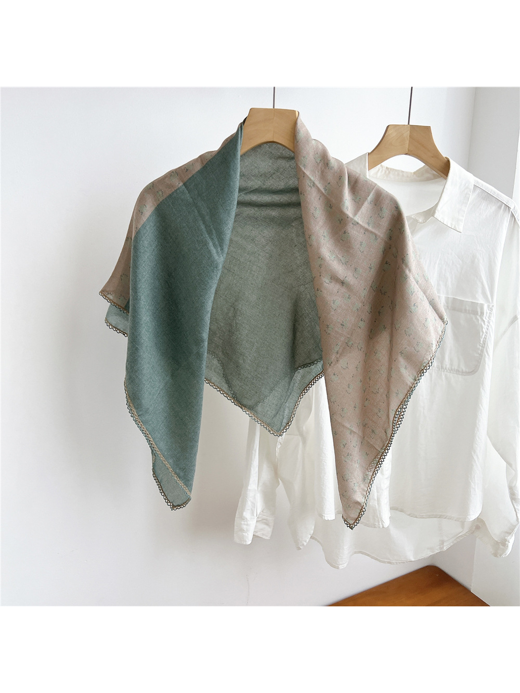 Two-tone green and blush floral scarf draped open on a hanger