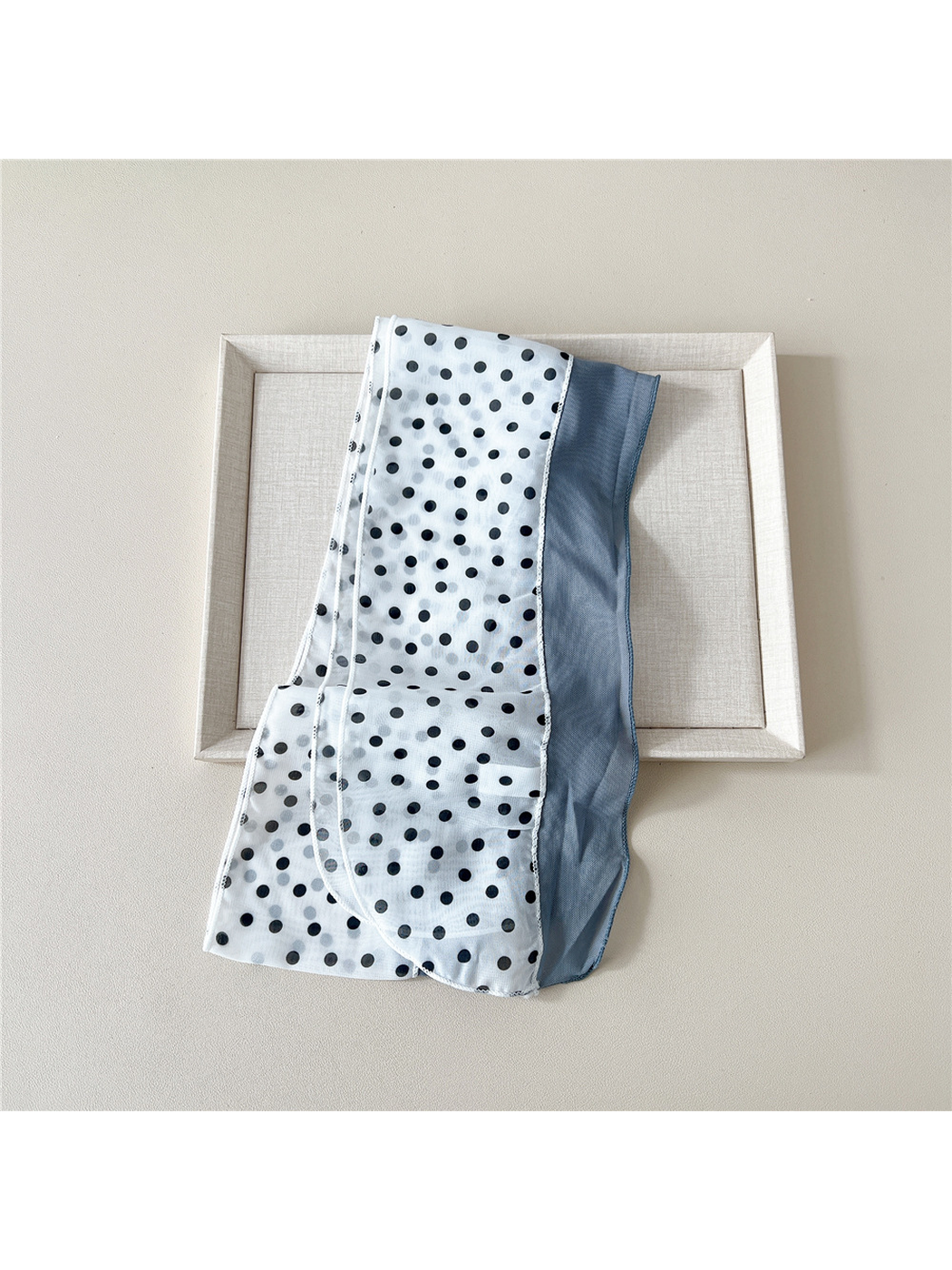 White dot scarf laid flat to show its rounded ends, stitched edges and contrasting lengthwise panels