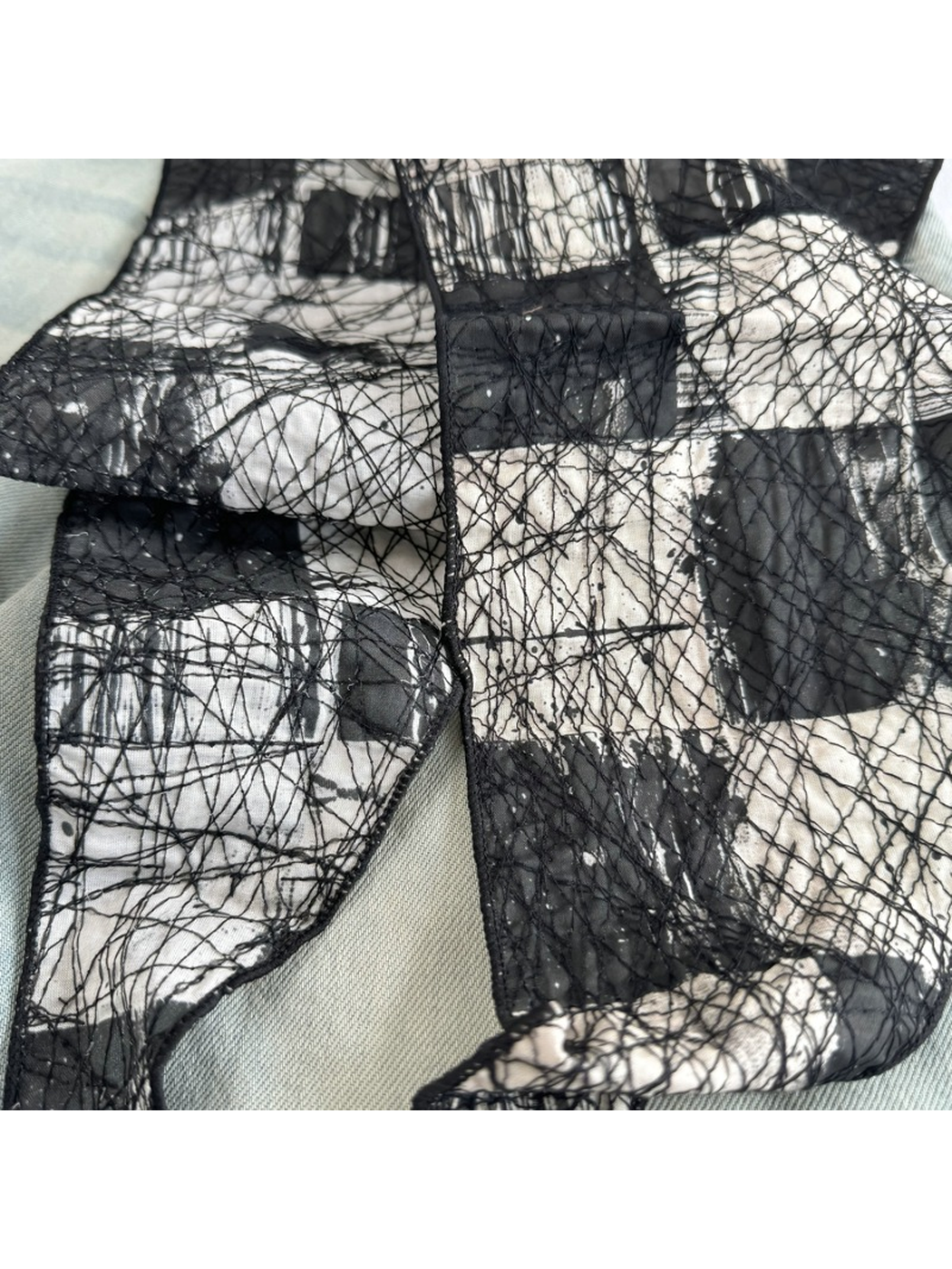 Close-up of the Black scarf block pattern, stitched edge and mesh texture