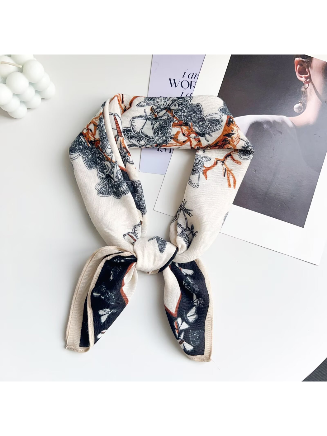 Cream butterfly-pattern square scarf arranged in a knotted loop