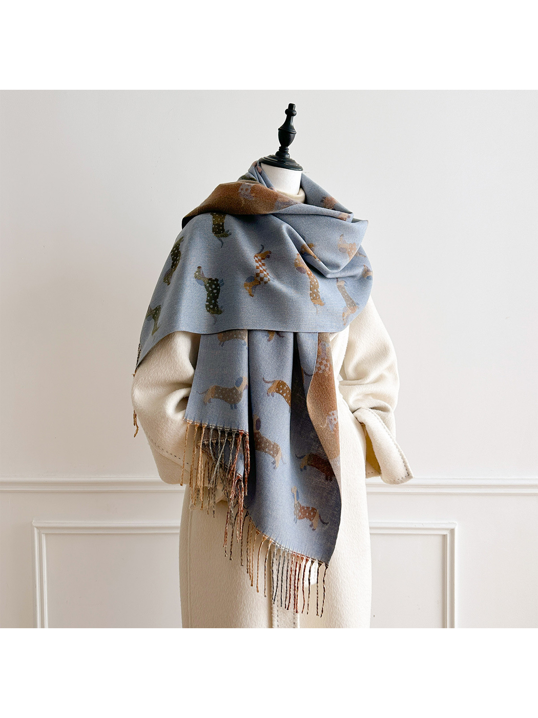 Blue Gray dachshund-pattern scarf draped broadly across a mannequin's shoulders, with an asymmetric front and hanging fringe.