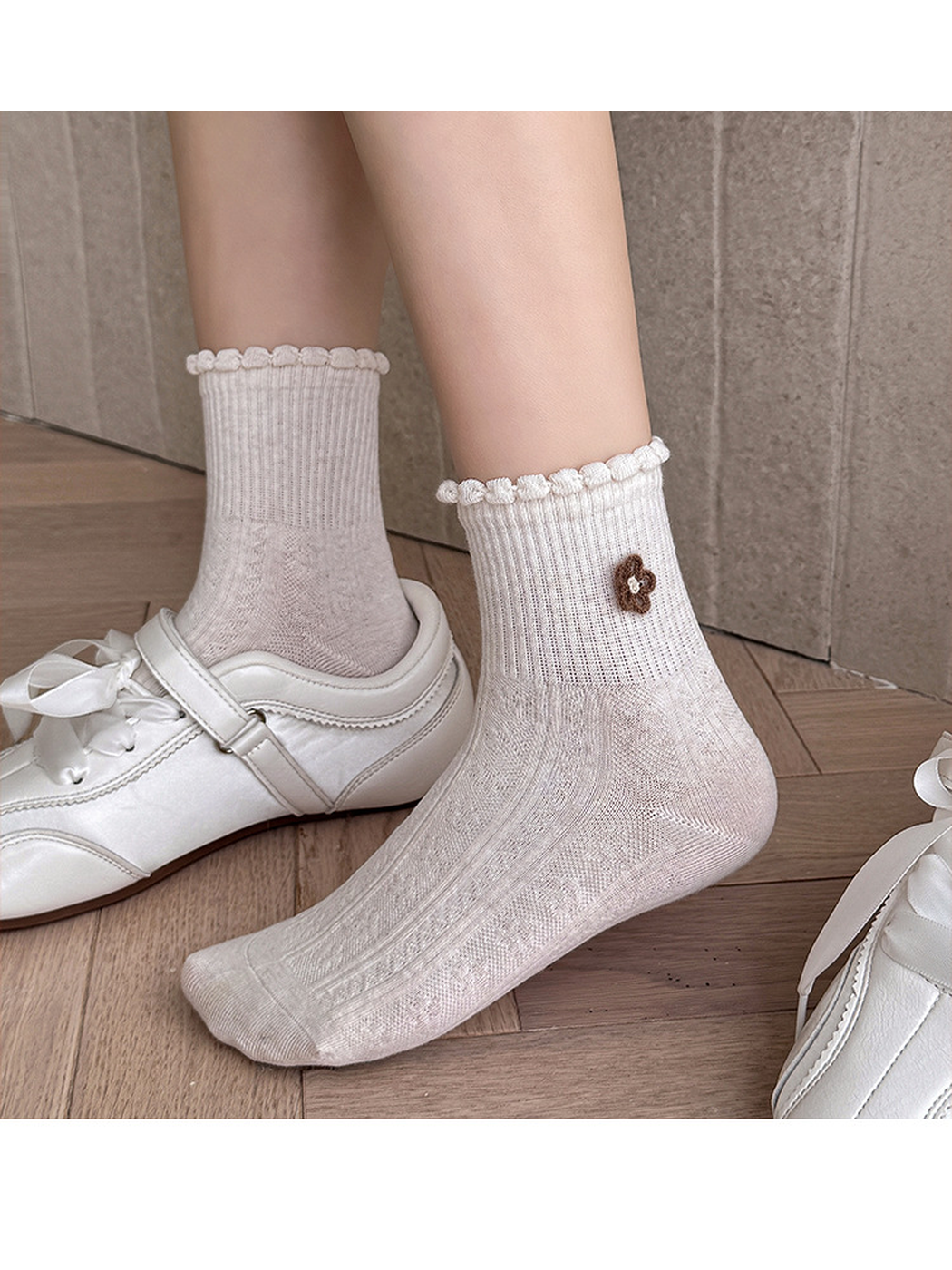 Ivory flower socks worn with one foot out of its shoe, showing the toe, shaped heel and ruffled cuff.