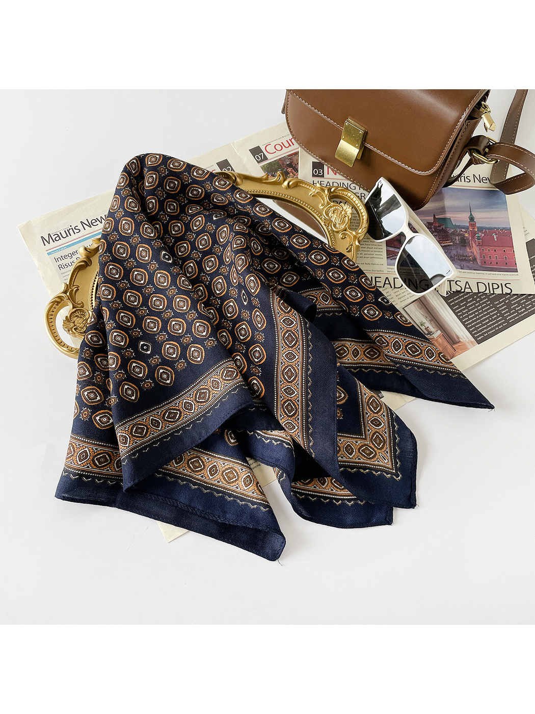 Navy geometric-pattern scarf draped on a tray with fashion accessories