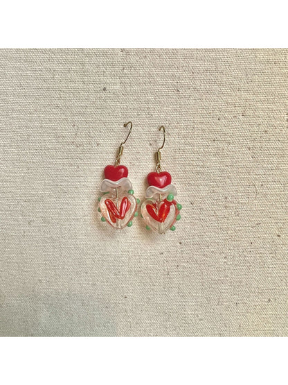 Pair of Earwish Playful Apple Heart Earrings placed on a wooden surface
