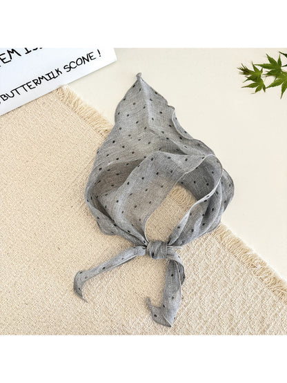 Close-up of soft fabric showing black polka dots on white textured head scarf