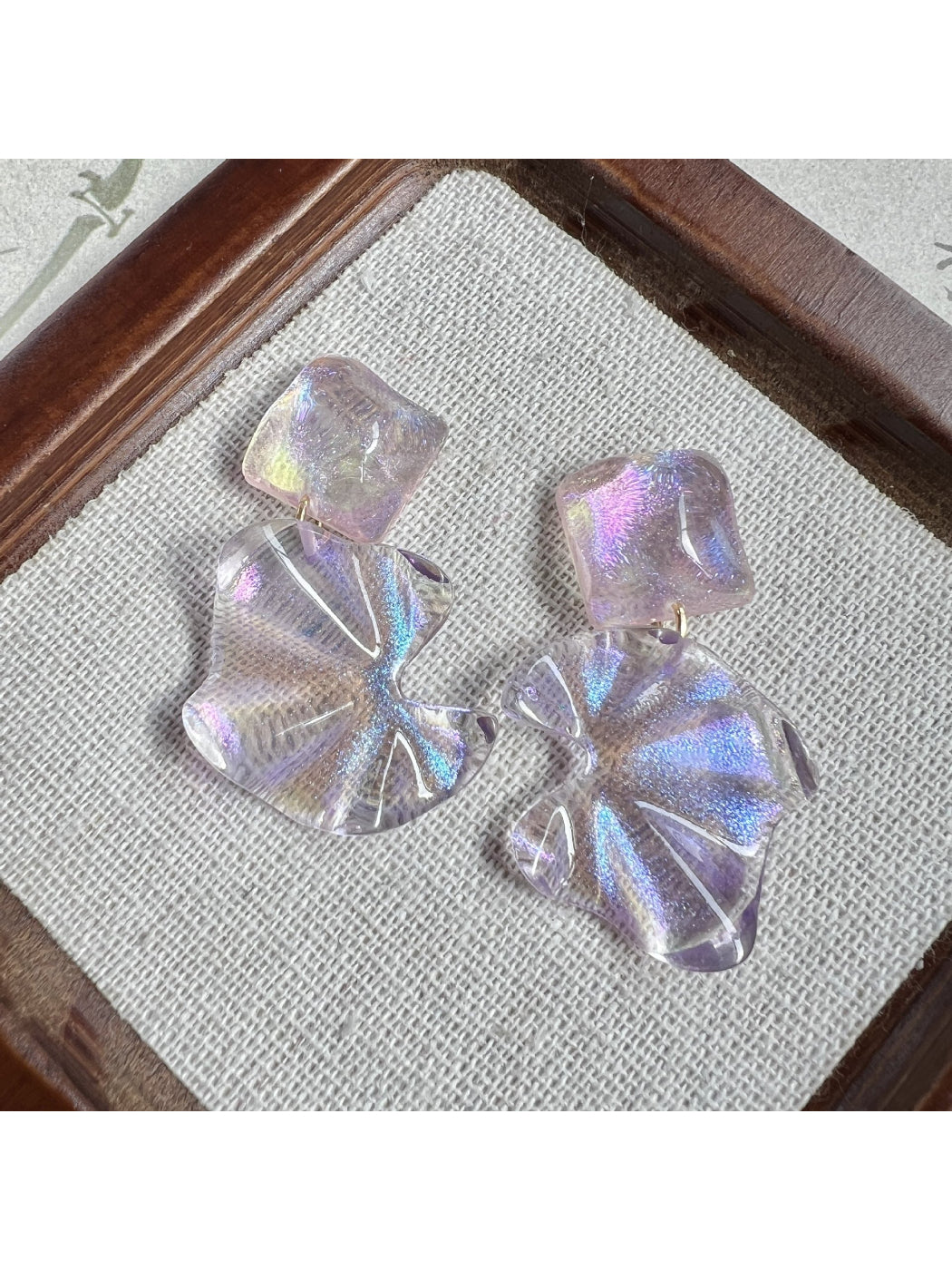 Pair of Earwish purple flower drop earrings laid flat on a wooden surface