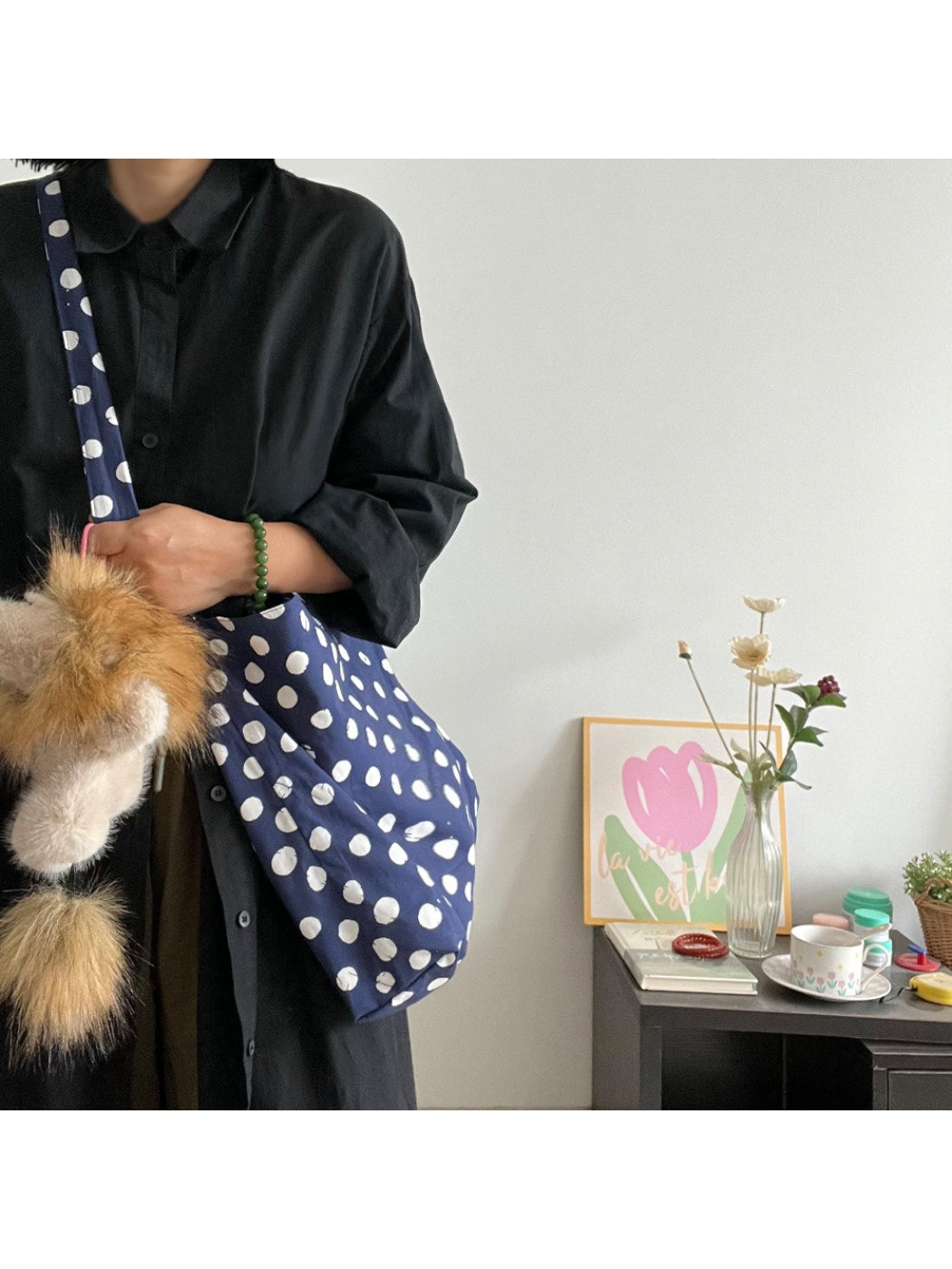 Navy shoulder bag with white polka dots and gold lion charm on front