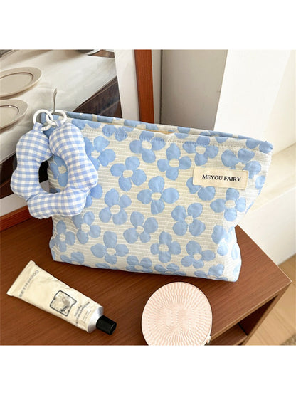 Cosbai cosmetic pouch with floral print placed next to makeup brushes and lipstick