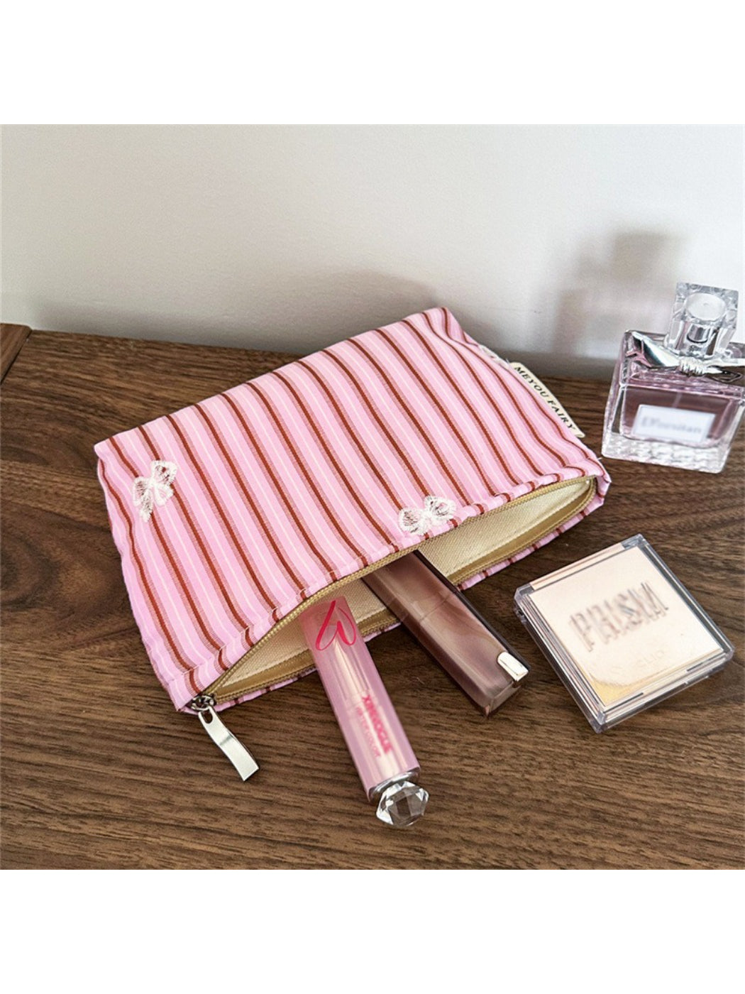 Pink stripe butterfly makeup bag displayed next to cosmetic items